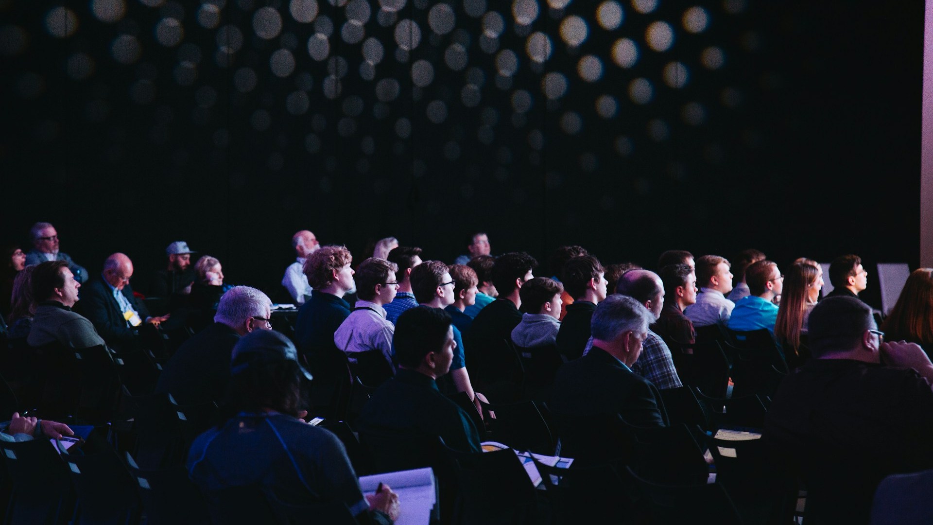 Conference attendees seated and listening to a speaker on stage